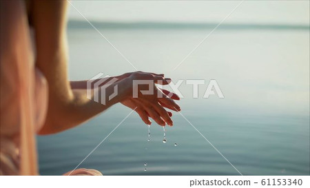 Woman hands in water inviting you over sunset golden rays. 61153340
