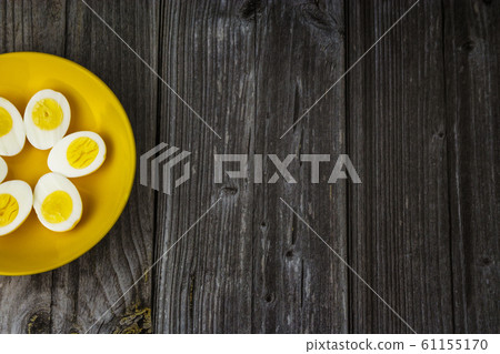 Boiled egg halves in a yellow bowl on wooden table 61155170
