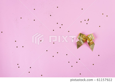 Gift or present bow and stars confetti on pink table, top view. Flat lay composition for birthday or other holidays Gift or present bow and stars confetti on pink table, top view. Flat lay composition for birthday or other holidays 61157922