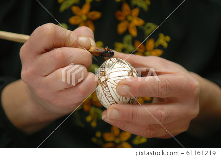 Craftswoman decorates egg before Easter Craftswoman decorates egg before Easter 61161219