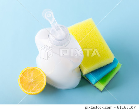Top view on white dishwashing liquid in a plastic bottle, lemon and three foam sponges. Top view on white dishwashing liquid in a plastic bottle, lemon and three foam sponges. 61163107