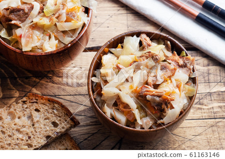 Stewed cabbage with meat in a wooden bowl on a 61163146