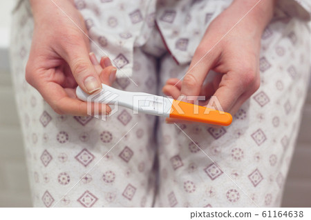 Rapid pregnancy test with negative result in woman's hand sitting in bathroom. 61164638