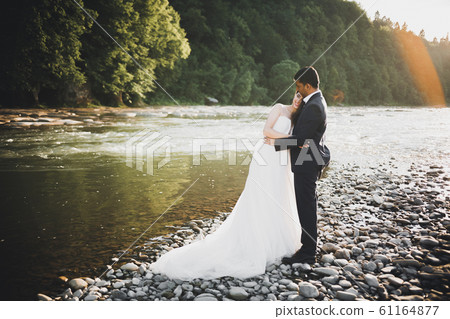 Wedding couple, groom and bride hugging, outdoor near river 61164877