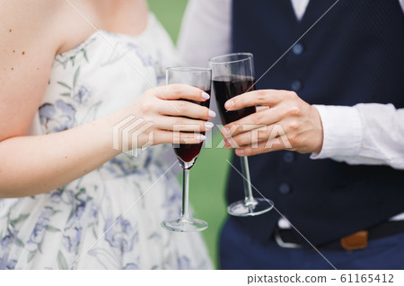 Bride and groom holding glasses with champagne and clink 61165412