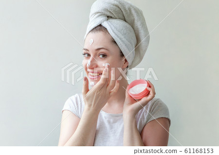 Minimal beauty woman girl in towel on head portrait applying white nourishing mask or creme on face isolated on white background. Skincare cleansing eco organic cosmetic spa concept. 61168153