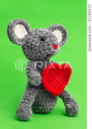 Grey knitted mouse with a heart in hand on a green 61168537