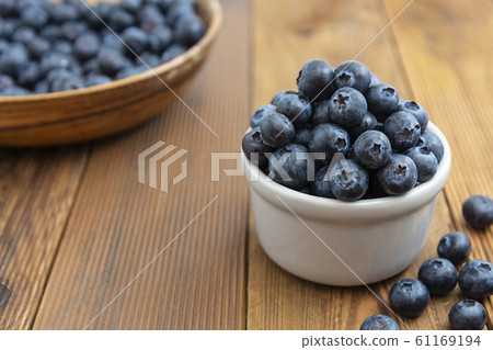 Ripe blueberries in the bowl on the wooden table. 61169194