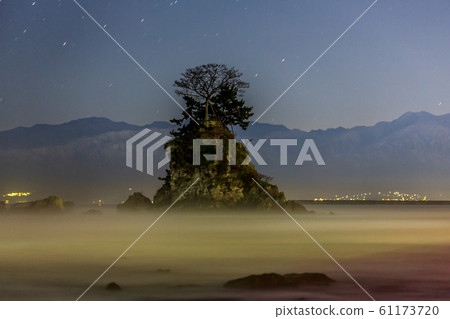 Starry sky rising over Meiwa and the Tateyama mountain range from the rainy shore before dawn 61173720