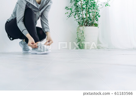 Woman tying shoelaces Woman tying shoelaces 61183566