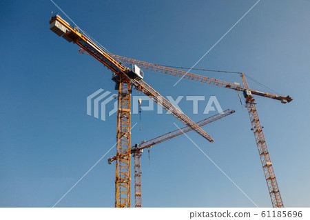 Luffing jib tower crane at large scale construction site with blue sky Luffing jib tower crane at large scale construction site with blue sky 61185696