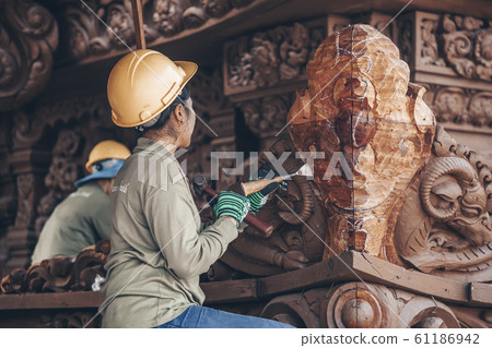 Carpenter - wood carving master performs artistic wood carving with special tools. Thailand, Pattaya Carpenter - wood carving master performs artistic wood carving with special tools. Thailand, Pattaya 61186942