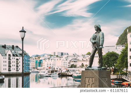 Alesund, Norway. Statue Of Young Sailor-fisher Boy On Brosundet Canal. Old Wooden Houses In Summer Day 61187611