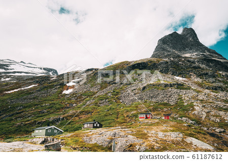 Trollstigen, Andalsnes, Norway. Wooden Houses In Mountains Landscape Near Road Trollstigen. Norwegian Landmark And Popular Destination. Norwegian County Road 63 In Sunny Summer Day 61187612