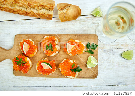 Salmon red caviar in bowl and Sandwiches with on wooden cutting board 61187837