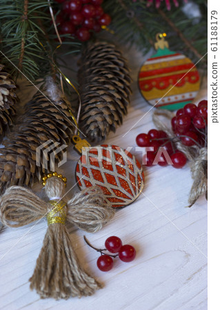 Xmas card. Christmas composition with Ukrainian doll-motanka, wooden Christmas balls, viburnum, cones and fir branches. New Year natural wooden toys. Xmas card. Christmas composition with Ukrainian doll-motanka, wooden Christmas balls, viburnum, cones and fir branches. New Year natural wooden toys. 61188179
