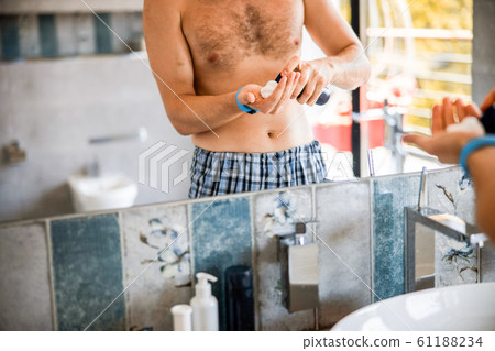 Young man spraying shaving foam on hand Young man spraying shaving foam on hand 61188234