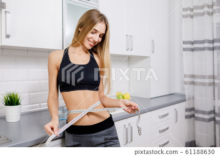 Slim Athletic Brunette Girl Measuring Her Waist 61188630