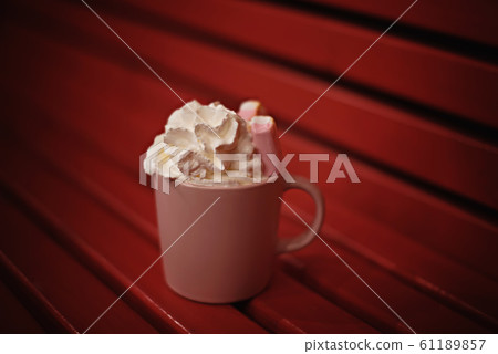 Coffee mug with cream and marshmallows on the red bench. 61189857