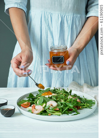 Woman watering arugula and shrimp salad  61190905