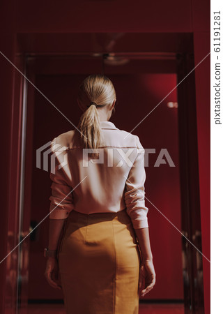 Stylish young woman standing in front of open door Stylish young woman standing in front of open door 61191281