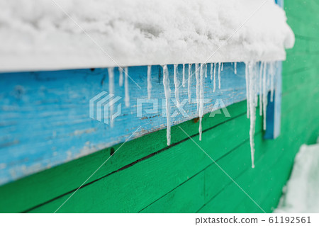 Icicles hang from the window of wooden house Icicles hang from the window of wooden house 61192561