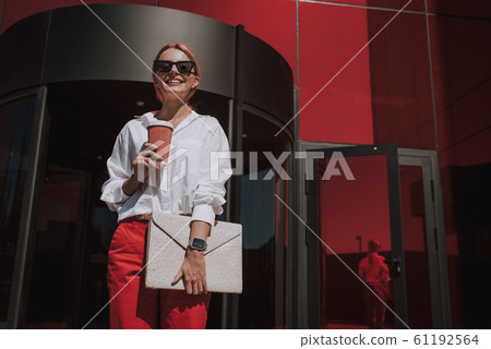 Cheerful elegant woman standing on the street Cheerful elegant woman standing on the street 61192564