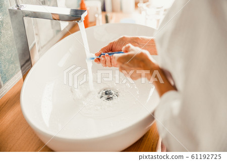 Senior lady washing toothbrush after brushing teeth Senior lady washing toothbrush after brushing teeth 61192725