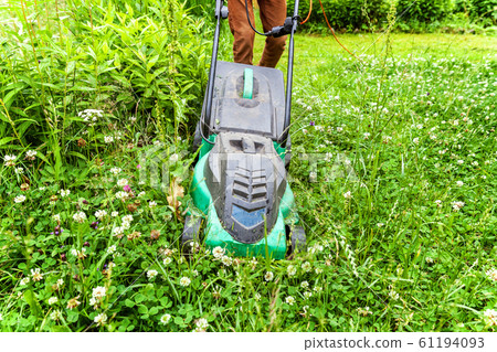 Man cutting green grass with lawn mower in Man cutting green grass with lawn mower in 61194093