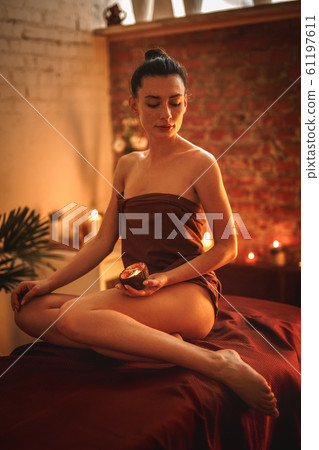 Alternative Medicine. Woman sitting in towel holding aroma candle 61197611