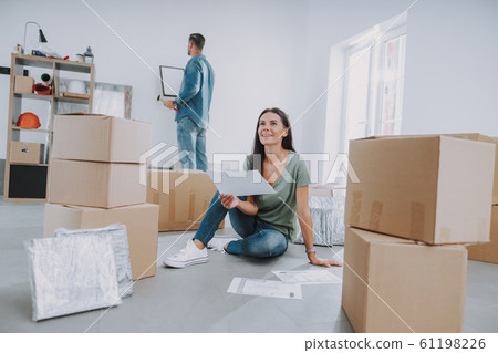 Smiling woman is siting near cardboard boxes in her new home Smiling woman is siting near cardboard boxes in her new home 61198226