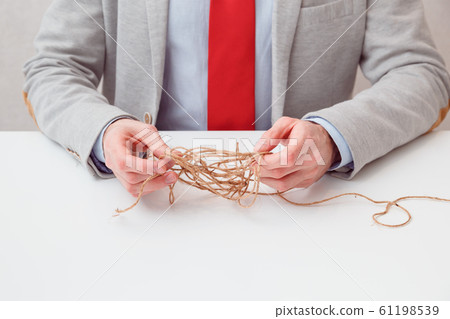 Alone businessman try to unwinds tangled thread ball like puzzle out situation. Conceptual photo. 61198539