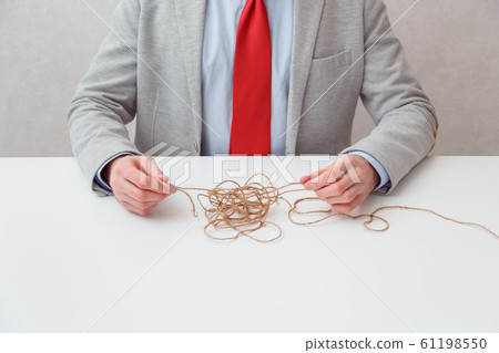 Alone businessman try to unwinds tangled thread ball like puzzle out situation. Conceptual photo. Alone businessman try to unwinds tangled thread ball like puzzle out situation. Conceptual photo. 61198550