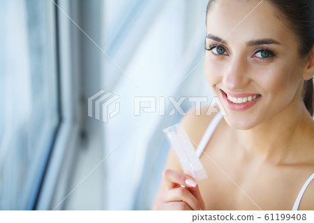 Teeth Whitening. Beautiful Smiling Woman Holding Whitening Strip. High Resolution Image 61199408