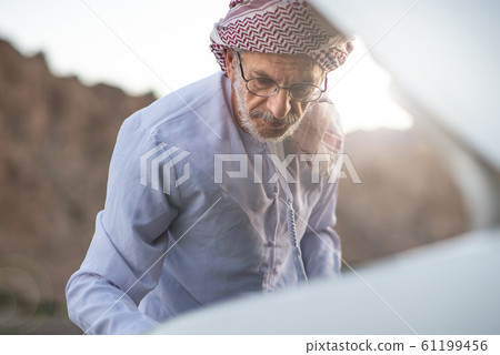 Arab man fixing his car outdoors 61199456