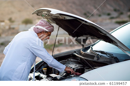 Arab man fixing his car outdoors Arab man fixing his car outdoors 61199457