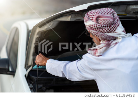 Arab man fixing his car outdoors Arab man fixing his car outdoors 61199458
