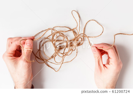 Man untangles a tangled thread. Top view isolated on a white background. 61200724