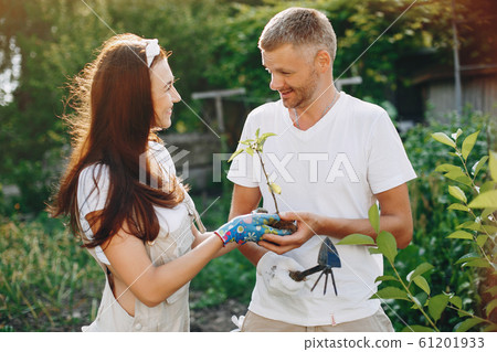 Beautiful couple works in a garden near the house Beautiful couple works in a garden near the house 61201933