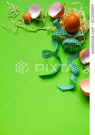Brown chicken egg in a straw nest, broken eggshell Brown chicken egg in a straw nest, broken eggshell 61203004