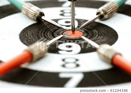 Close-up dart arrow hitting target centre Close-up dart arrow hitting target centre 61204386