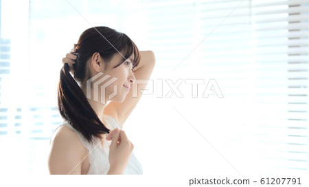 A woman tying her hair 61207791