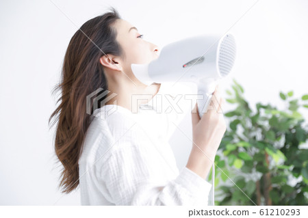 A woman using a hair dryer 61210293