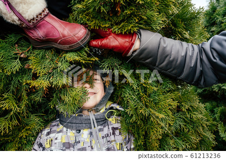 Funny winter composition a boy in a hat, a female hand and a children's red boot Funny winter composition a boy in a hat, a female hand and a children's red boot 61213236