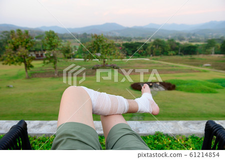 Man resting outdoor on a grass field with bandage legs Man resting outdoor on a grass field with bandage legs 61214854
