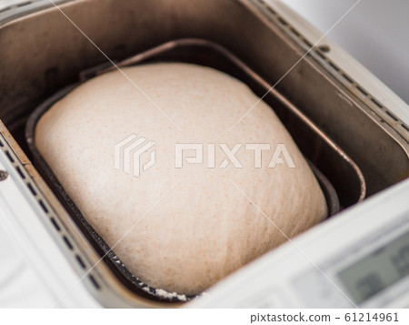 Tasty sliced loaf and bread machine on table 61214961