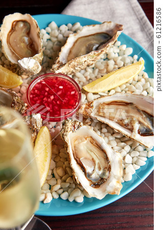 Platter of fresh opened oysters and wine. 61216586