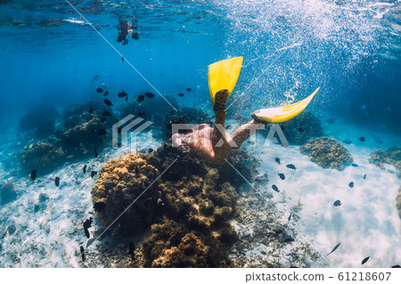 Freediver girl with fins glides over sandy bottom in blue ocean 61218607