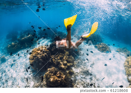 Freediver girl with fins glides over sandy bottom in blue ocean 61218608