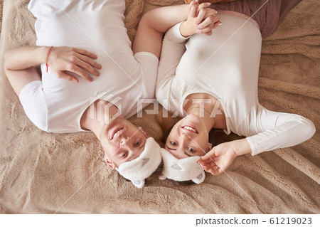 Pair in love lying on bed. Portrait of man and woman looking at camera. Top view of friends in . . Young happy couple beat the pillows on the bed in a bedroom at home 61219023